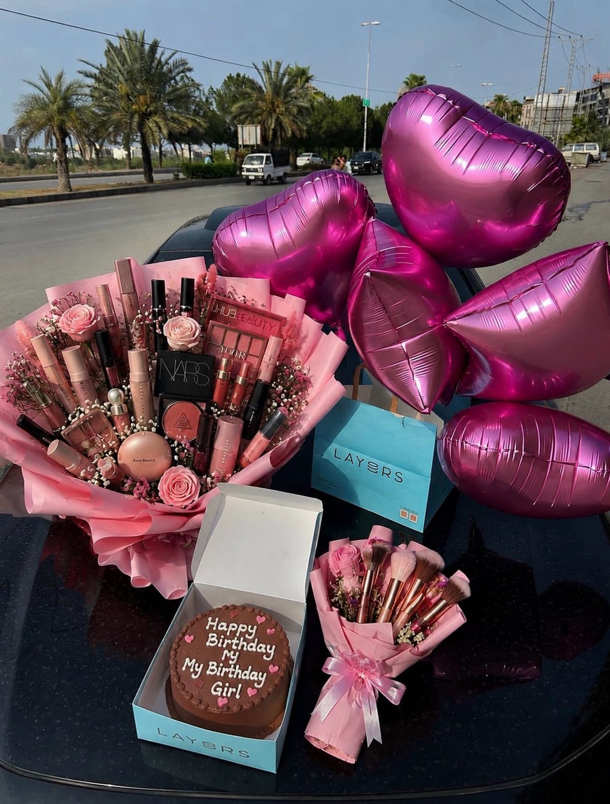 Gift set with makeup bouquets, heart balloons, and a personalized birthday chocolate cake.
