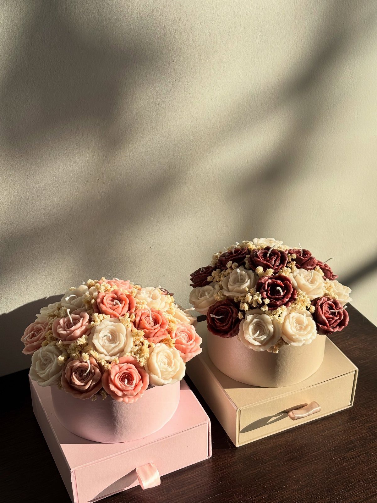Two elegant hat boxes filled with preserved roses in pink and burgundy tones.