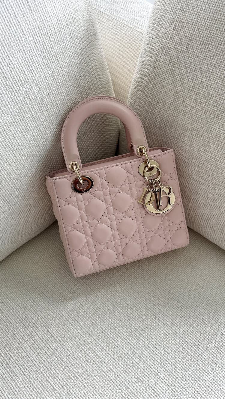 Small pink quilted leather handbag with gold hardware on white textured fabric