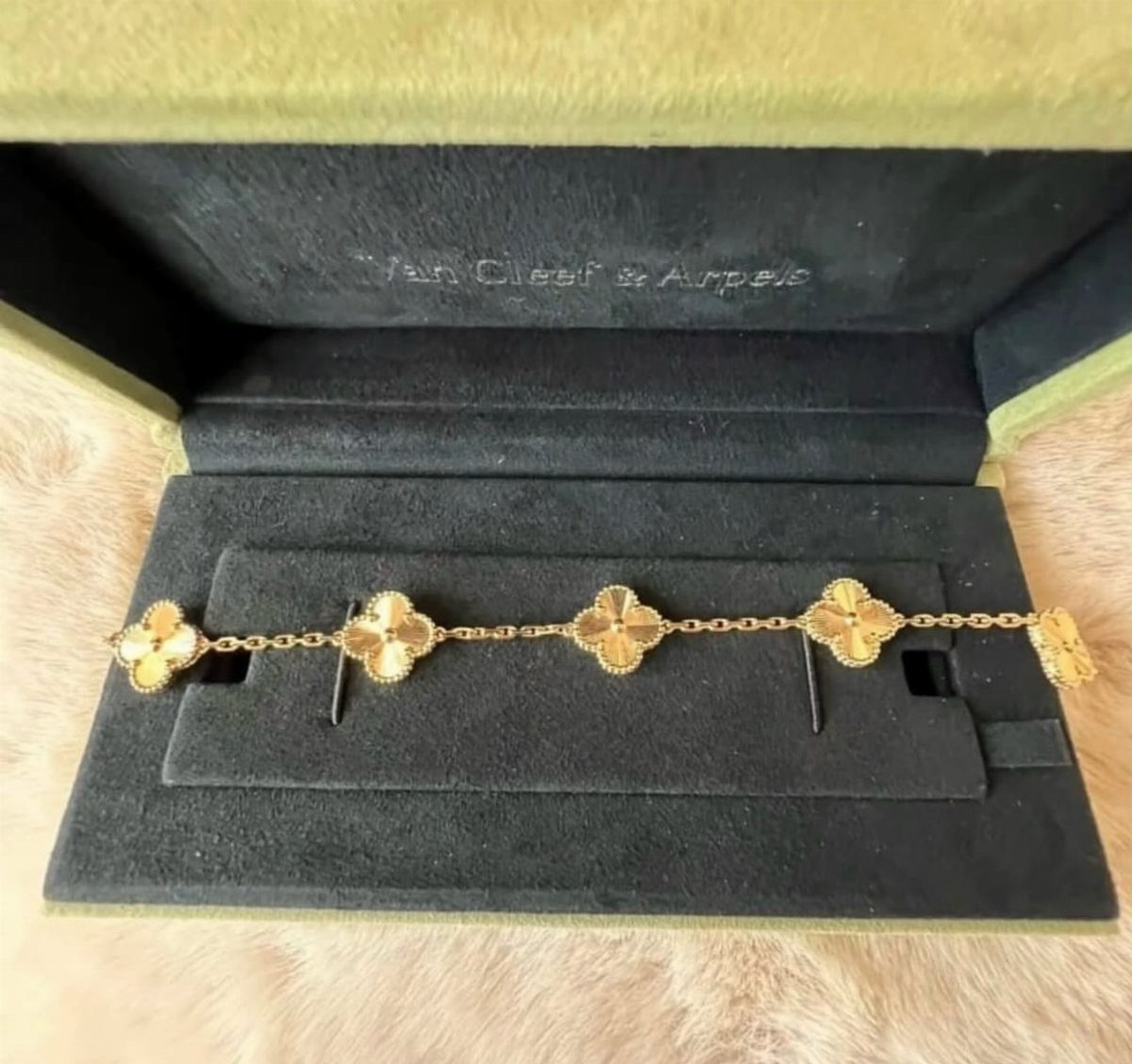Gold clover bracelet resting inside a black velvet Van Cleef and Arpels box