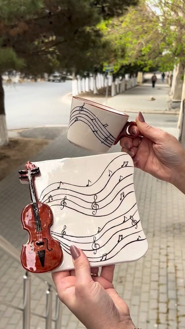 Music-themed ceramic mug and plate with a 3D violin sculpture held by hands.