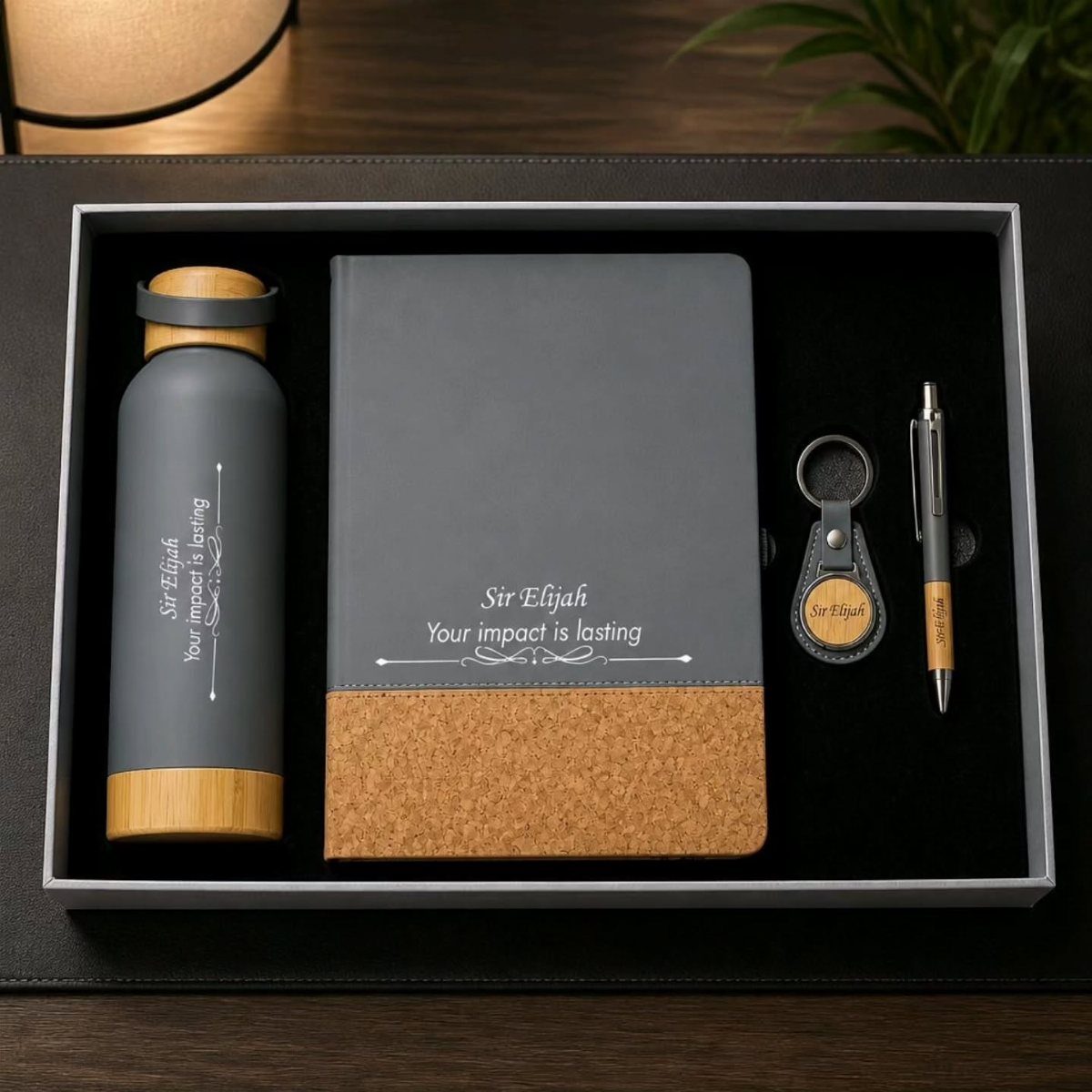 Personalized gift set with grey notebook, water bottle, pen, and keychain in box