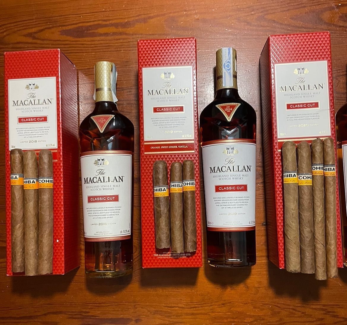 Macallan scotch whiskey bottles and Cohiba cigars arranged on a wooden table.