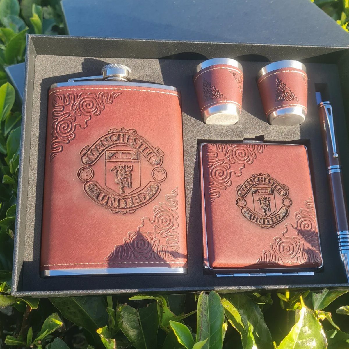 Brown leather gift set with Manchester United logo including flask, cups, and pen.