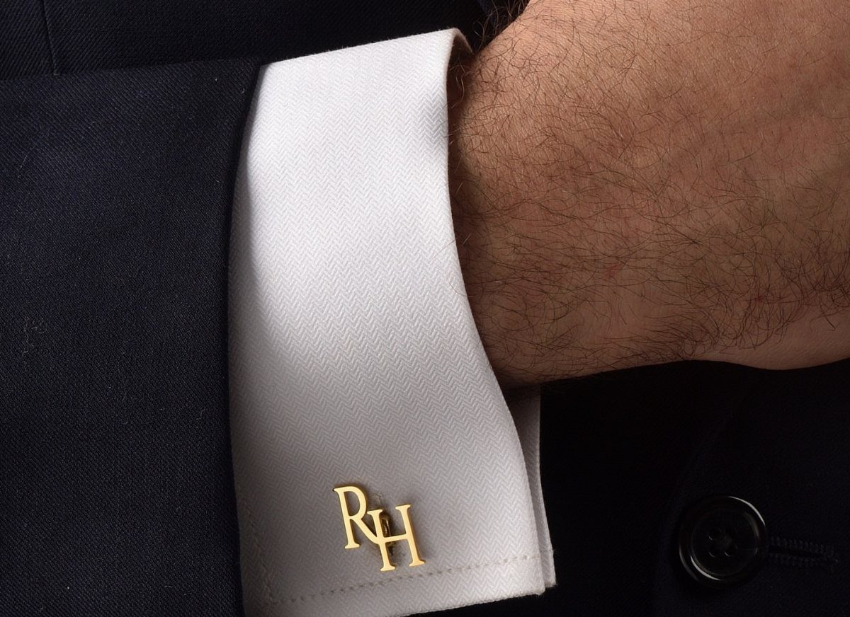 Gold cufflinks with initials RH on a white dress shirt cuff and suit