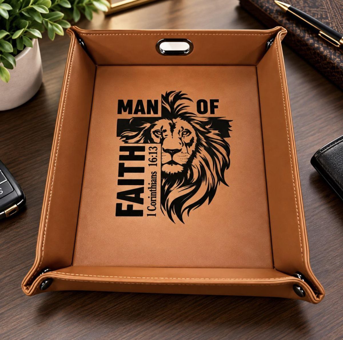 Brown leather valet tray with a lion design and faith text on a desk