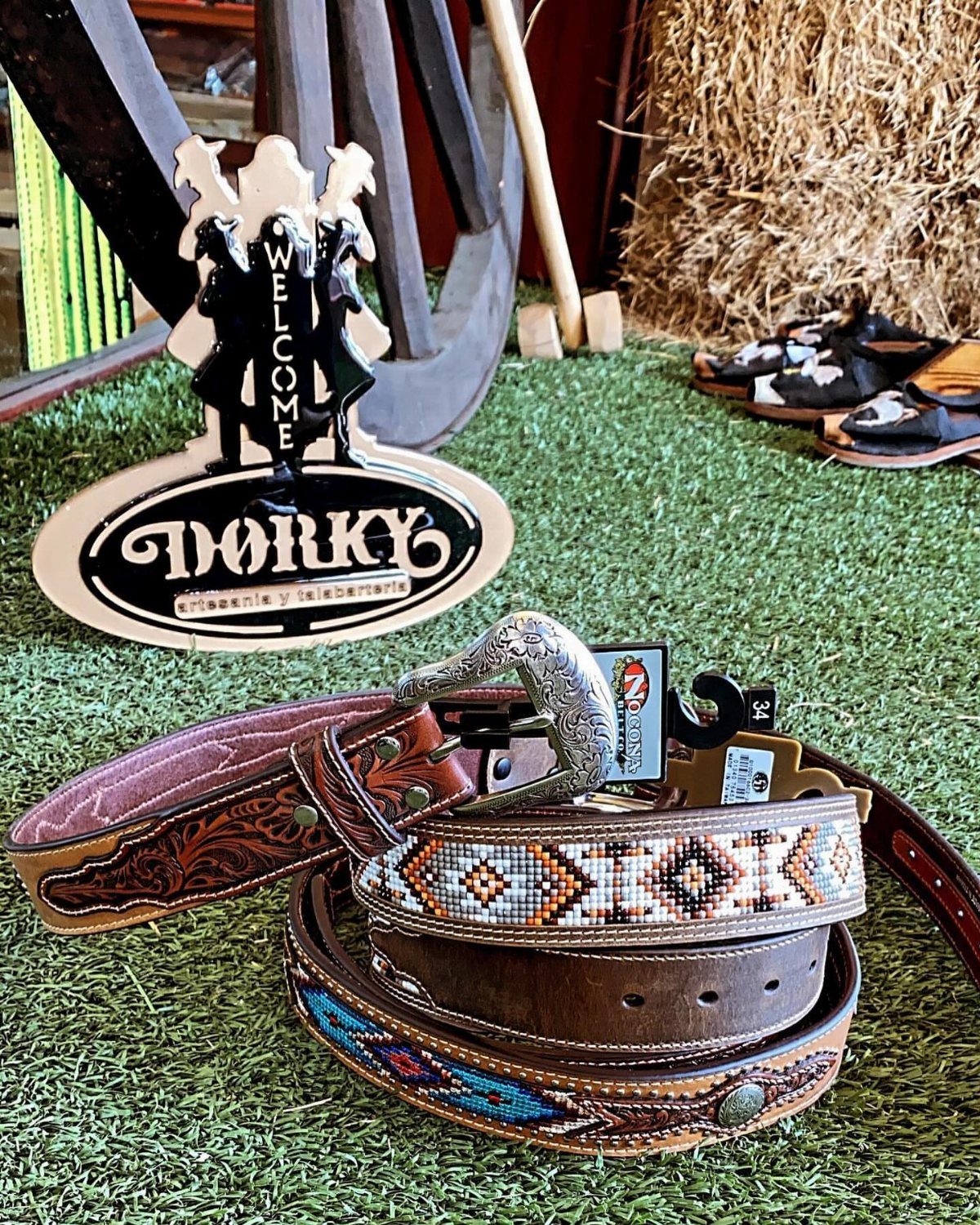 Embroidered brown leather piteado belt with silver buckle on green artificial grass