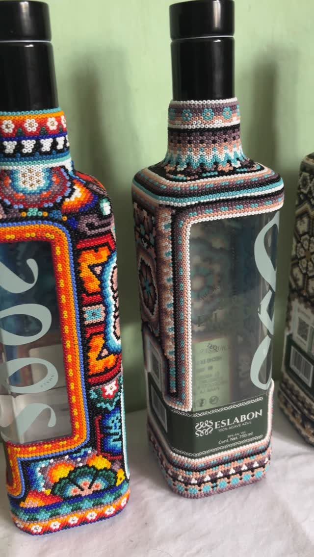 Two liquor bottles decorated with colorful, intricate beaded covers in geometric patterns.
