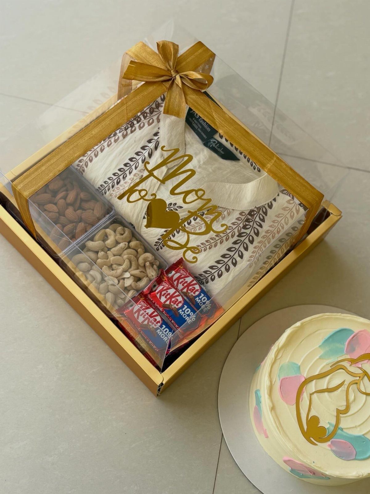 Gift box with Mom to be shirt and nuts beside a pregnancy cake