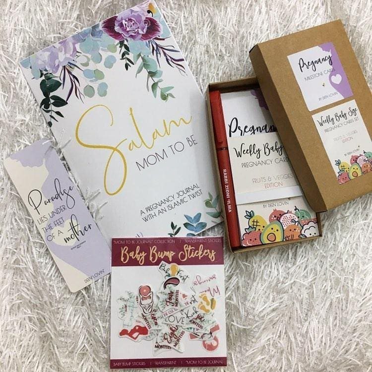 Pregnancy journal, milestone cards, and baby bump stickers on a white fluffy background.