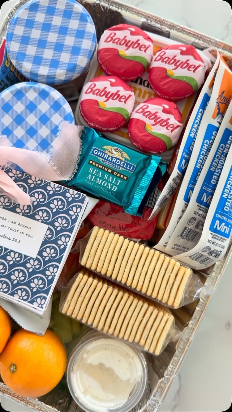 Snack basket in a foil tray with cheese, chocolate, crackers, and oranges.