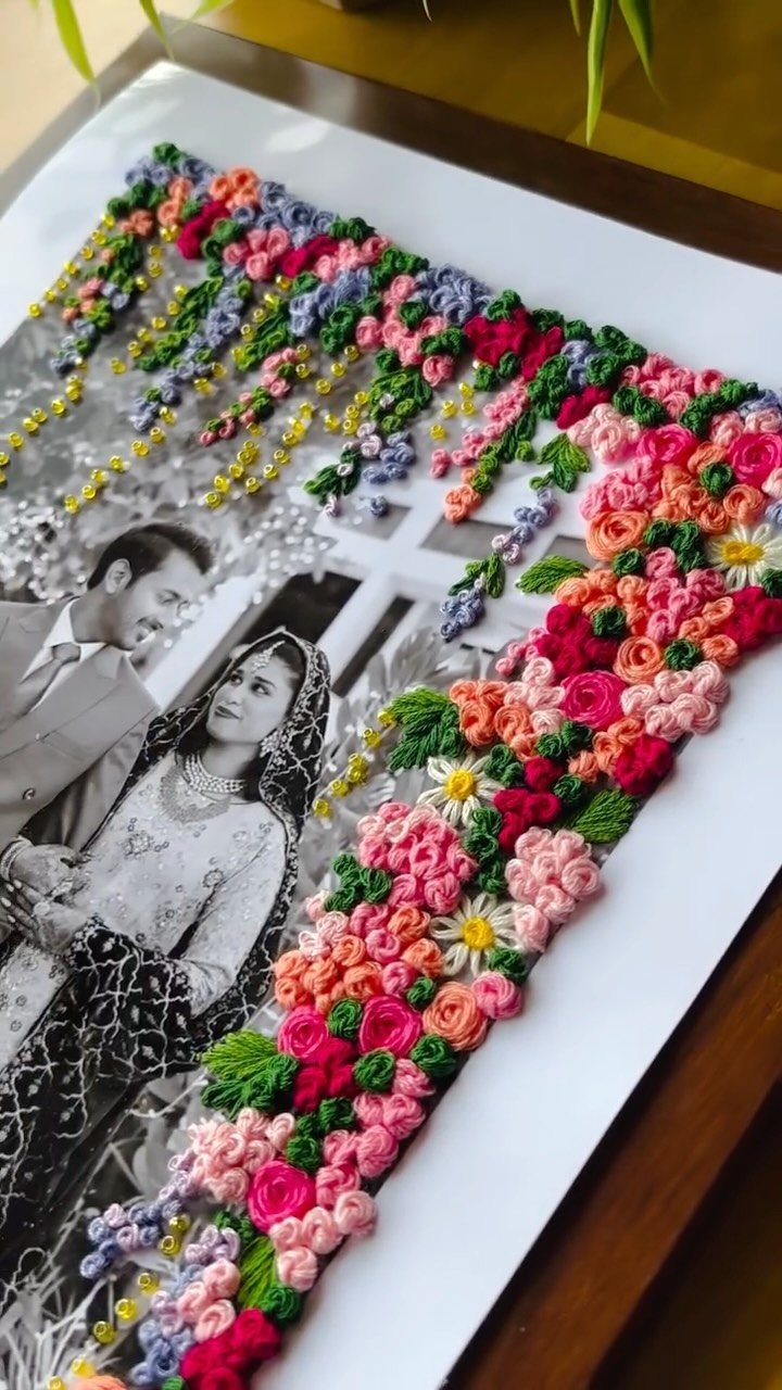 Black and white couple portrait with a colorful 3D embroidered floral border.