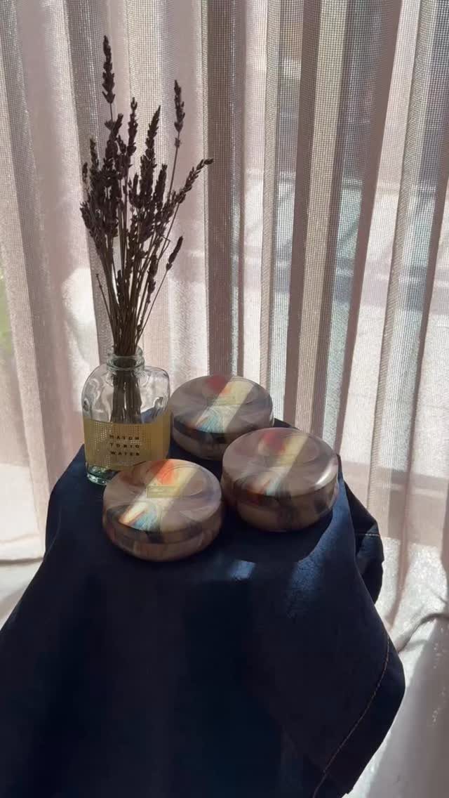 Three colorful patterned coasters and dried lavender in a vase on blue fabric.