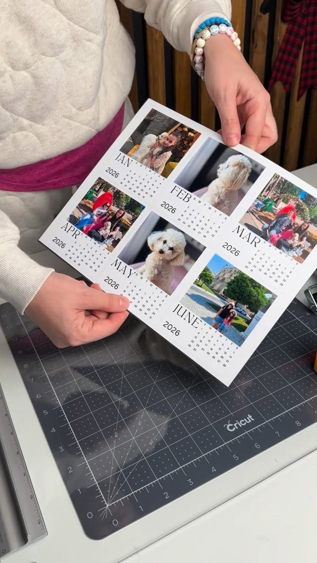 Hands holding a personalized photo calendar page over a grey Cricut cutting mat.