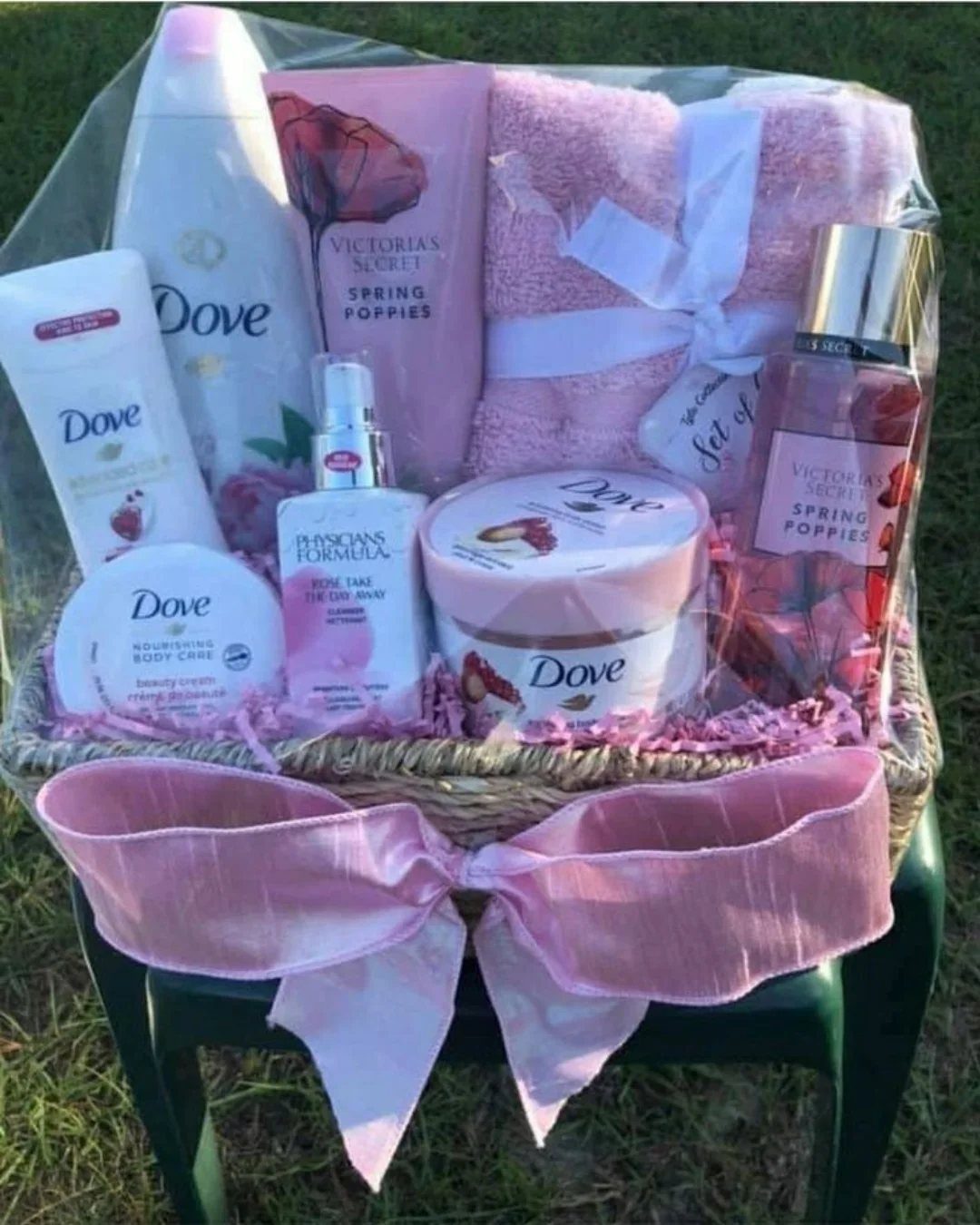 Wicker gift basket filled with pink spa products, lotions, and a towel.