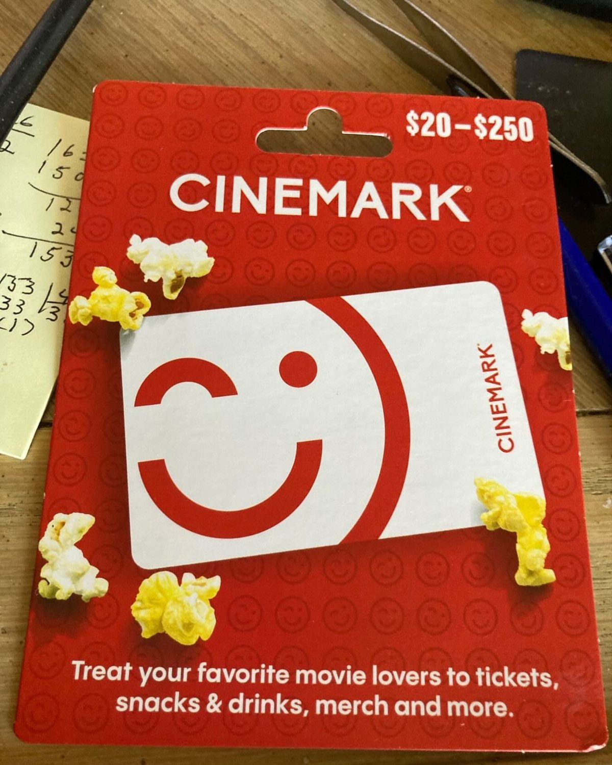 Cinemark movie theater gift card on a red holder with scattered popcorn kernels.