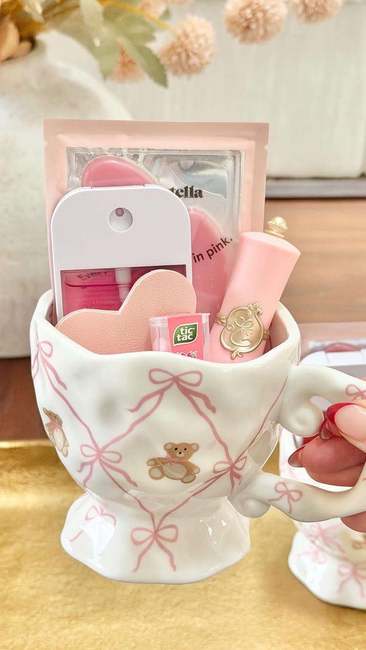 Decorative white mug filled with pink beauty products and a heart sponge.