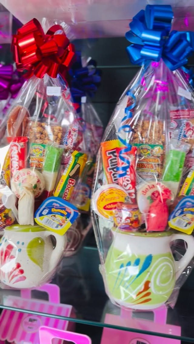 Two white mugs filled with colorful candies wrapped in cellophane with bright bows.