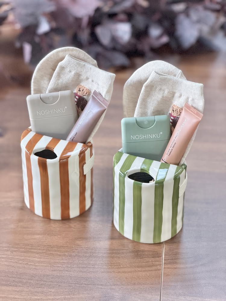 Two striped mugs filled with white socks, lotion tubes, and small containers.