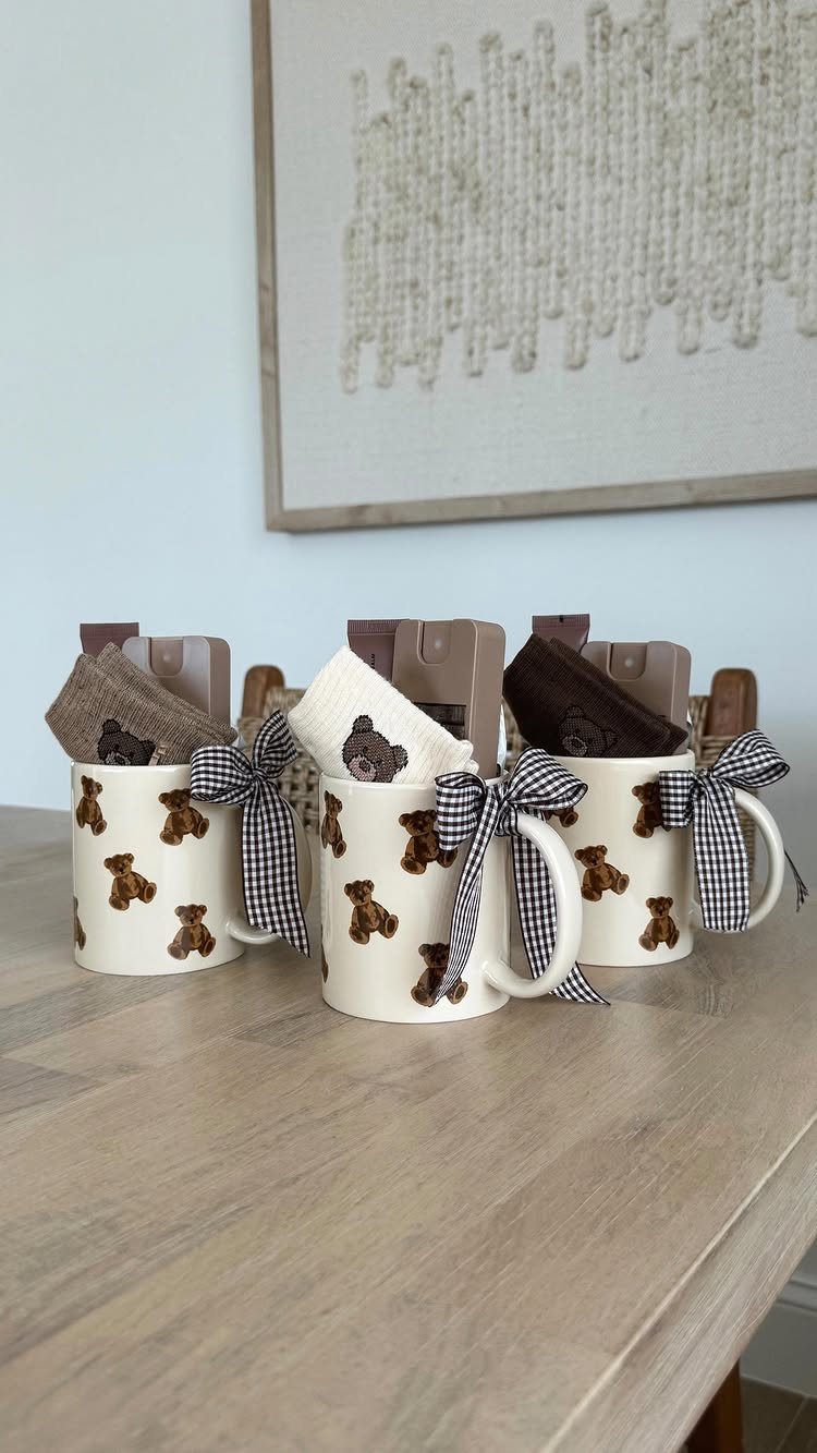 Three teddy bear patterned mugs filled with small gifts and checkered bows.