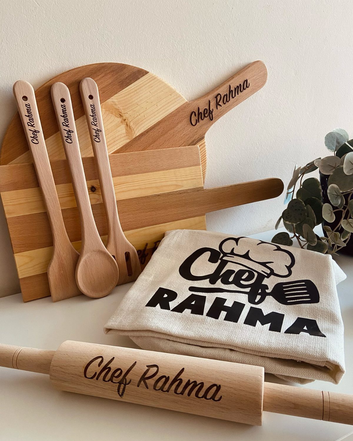 Engraved wooden cutting board, rolling pin, and utensils with a matching personalized apron.