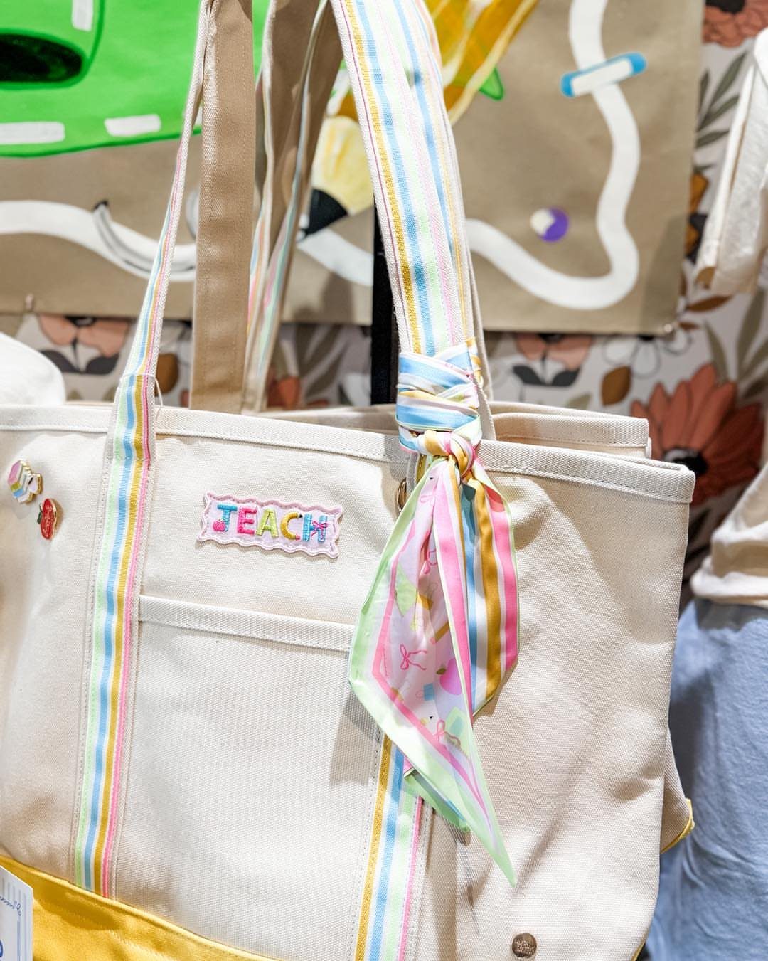 Canvas tote bag with colorful striped straps and a TEACH patch.