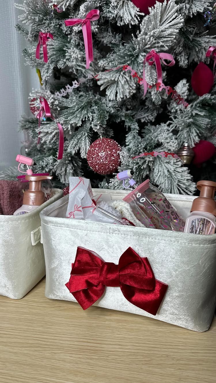 White gift bins with red bows filled with beauty products before a Christmas tree