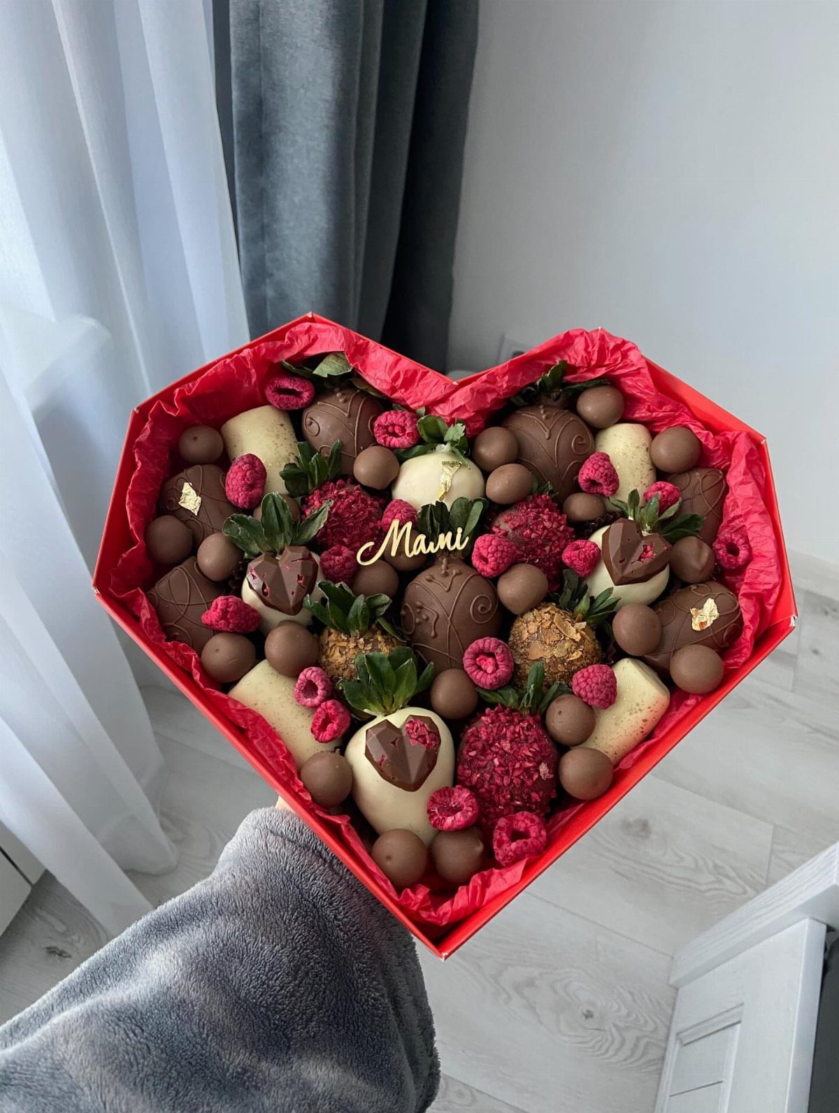 Heart-shaped red gift box filled with chocolate-covered strawberries and raspberries for Mami