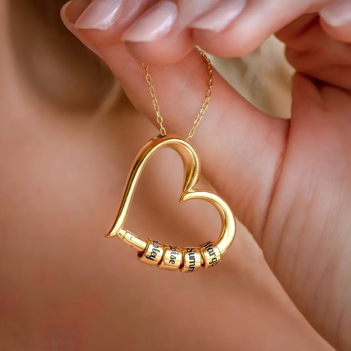 Gold heart-shaped necklace with small personalized name beads sliding on the pendant