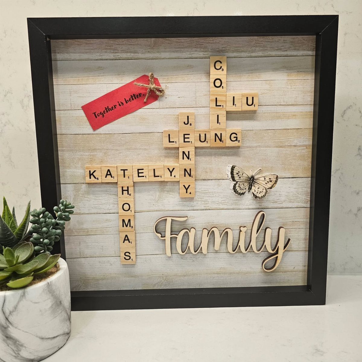 Family name crossword puzzle made of wooden tiles in a black shadow box frame