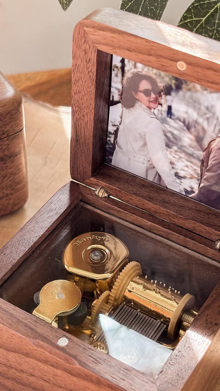 Wooden music box with a gold mechanism and a family photo on the lid