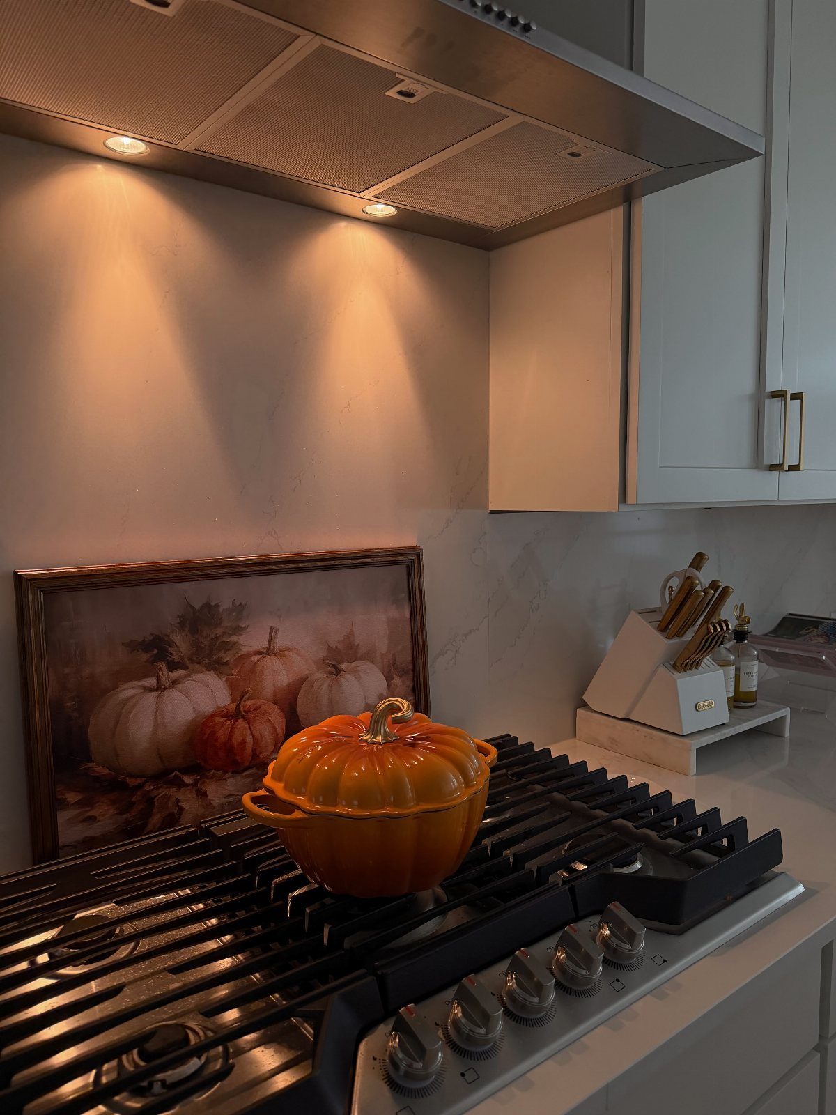 Orange pumpkin-shaped Dutch oven on a black gas stove in a kitchen