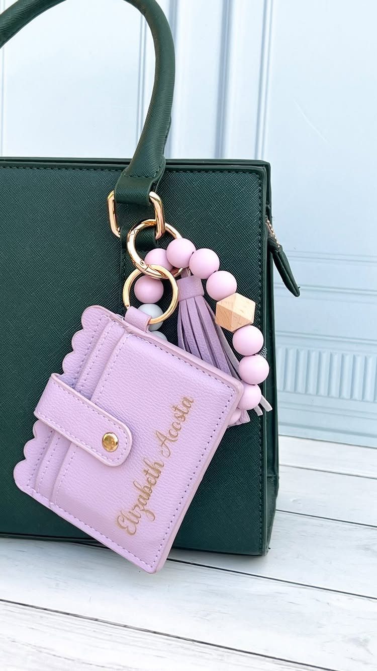 Purple personalized wristlet with beaded strap attached to a dark green handbag