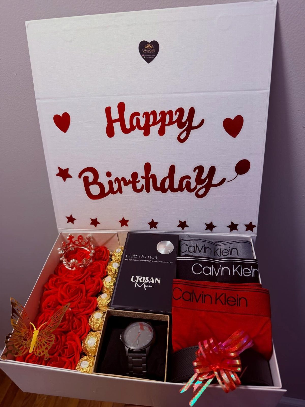 Birthday gift box with a watch, Calvin Klein underwear, perfume, and red roses.