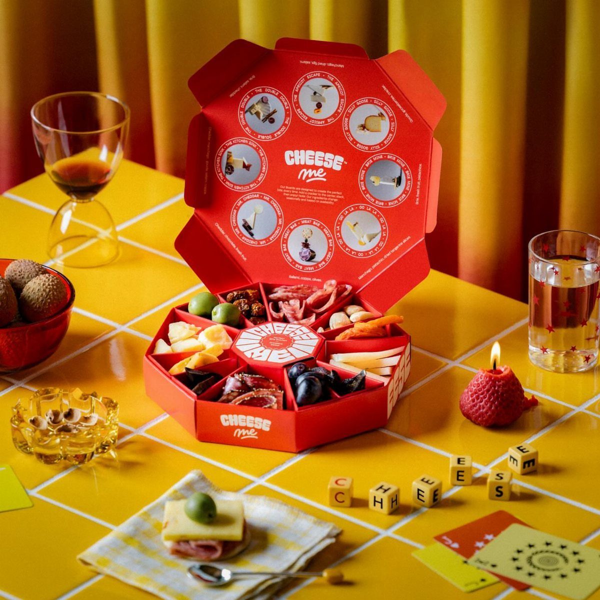 Red octagonal gift box filled with gourmet meats and cheeses on yellow table