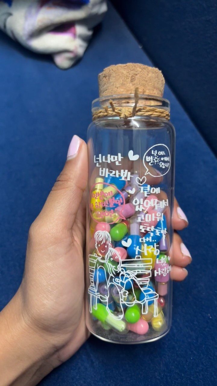 Glass jar filled with colorful candy pills and white Korean text and illustrations.