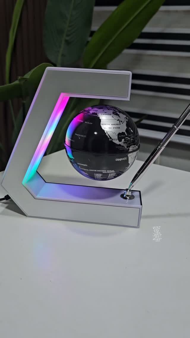 Floating black globe levitating inside a glowing C-shaped white frame on a table
