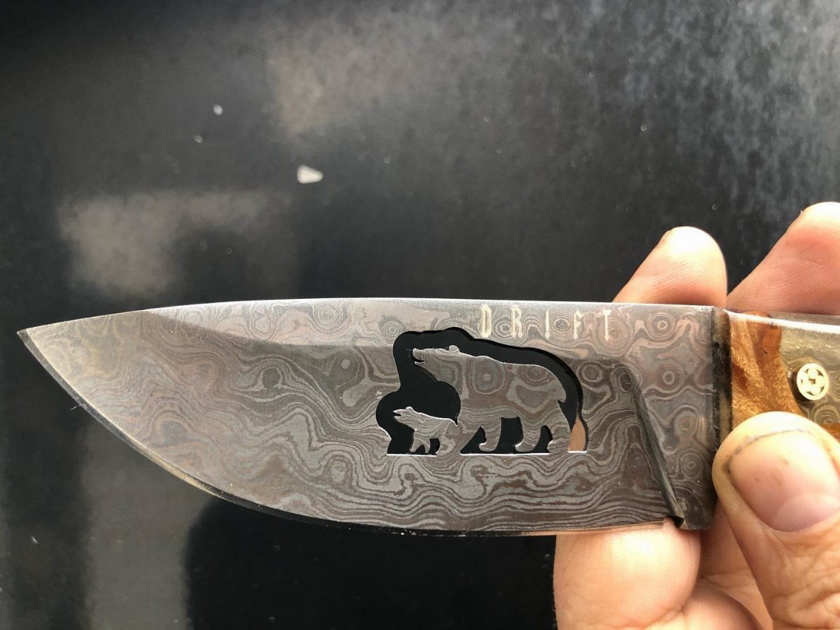 Knife blade with a bear and cub silhouette and the word DRIFT engraved.