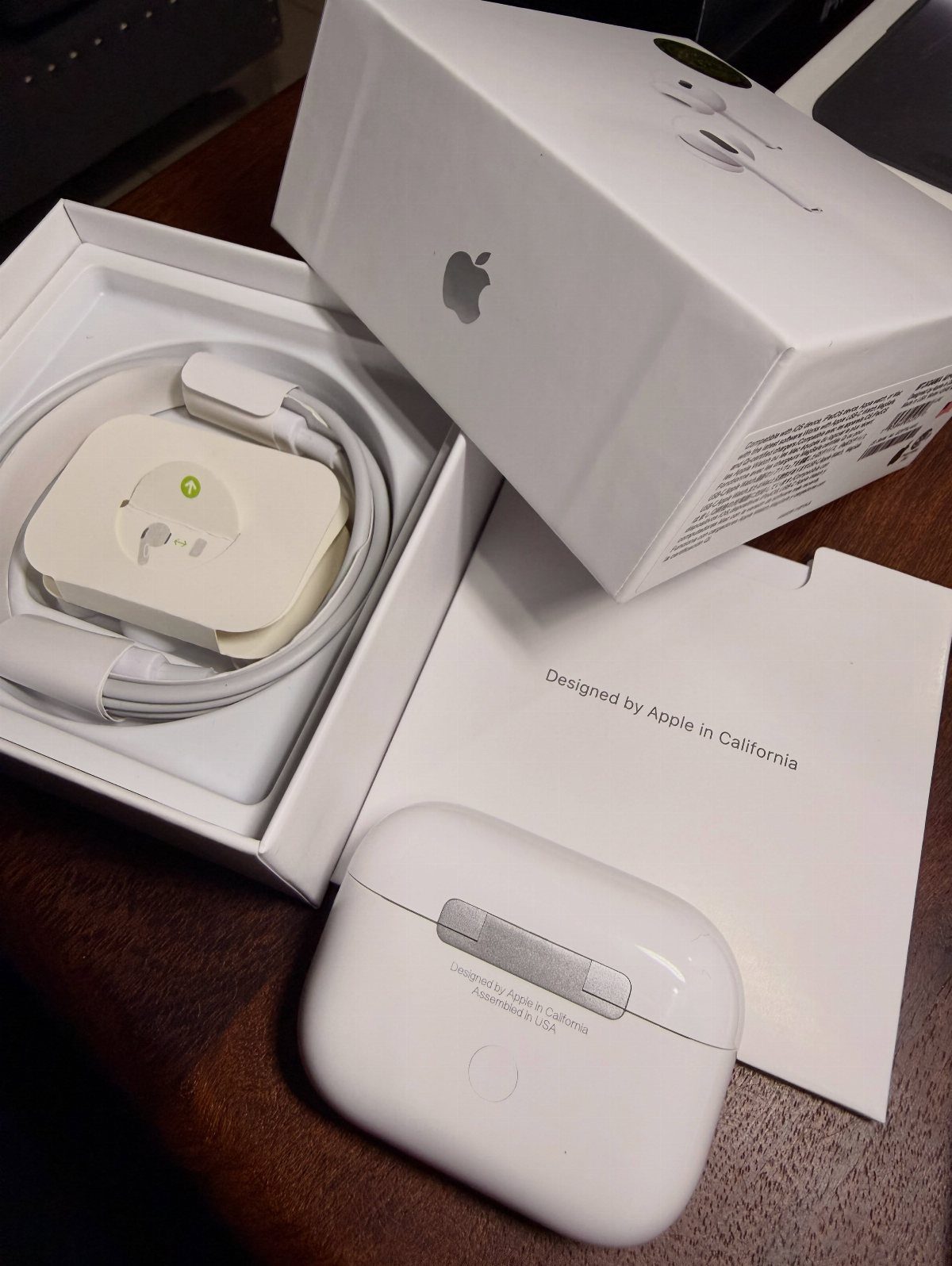 Apple AirPods wireless earbuds and charging case with original white packaging on wood.