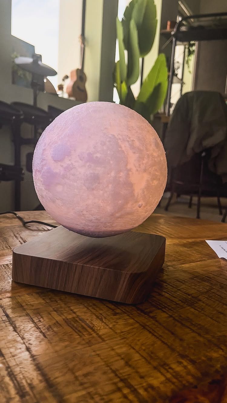 Levitating 3D moon lamp glowing purple on a wooden base and table