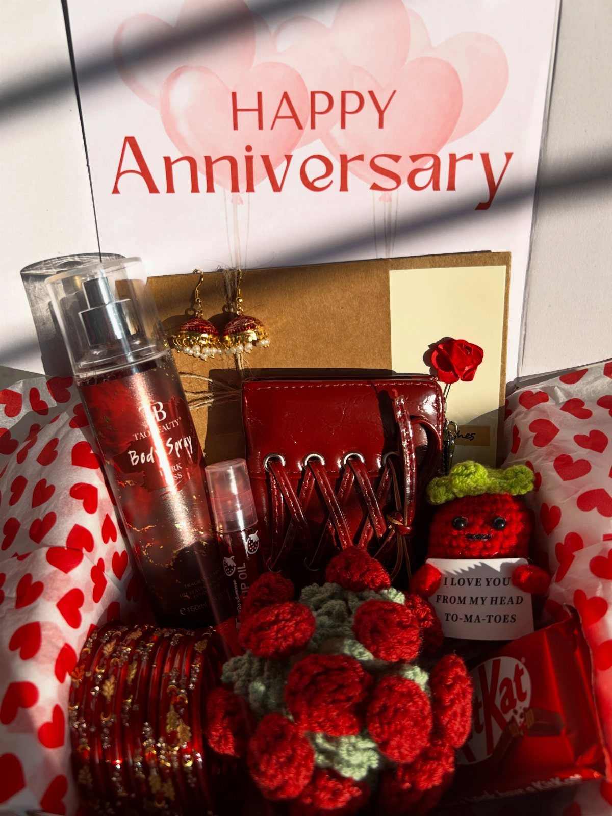 Gift hamper with red accessories, body spray, and anniversary card for a girlfriend.