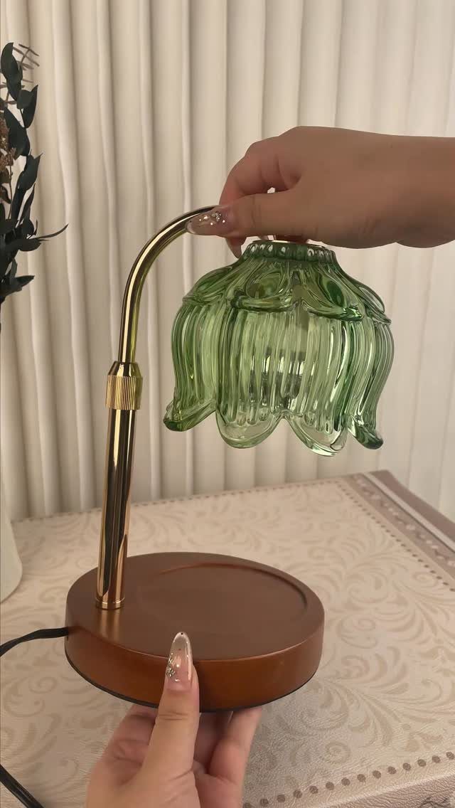 Small desk lamp with a green flower-shaped glass shade and gold metal arm.