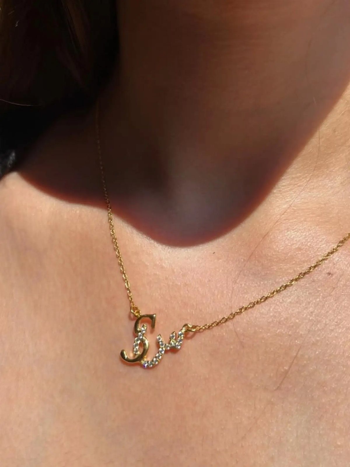 Gold Arabic calligraphy necklace with diamonds worn on a person's neck