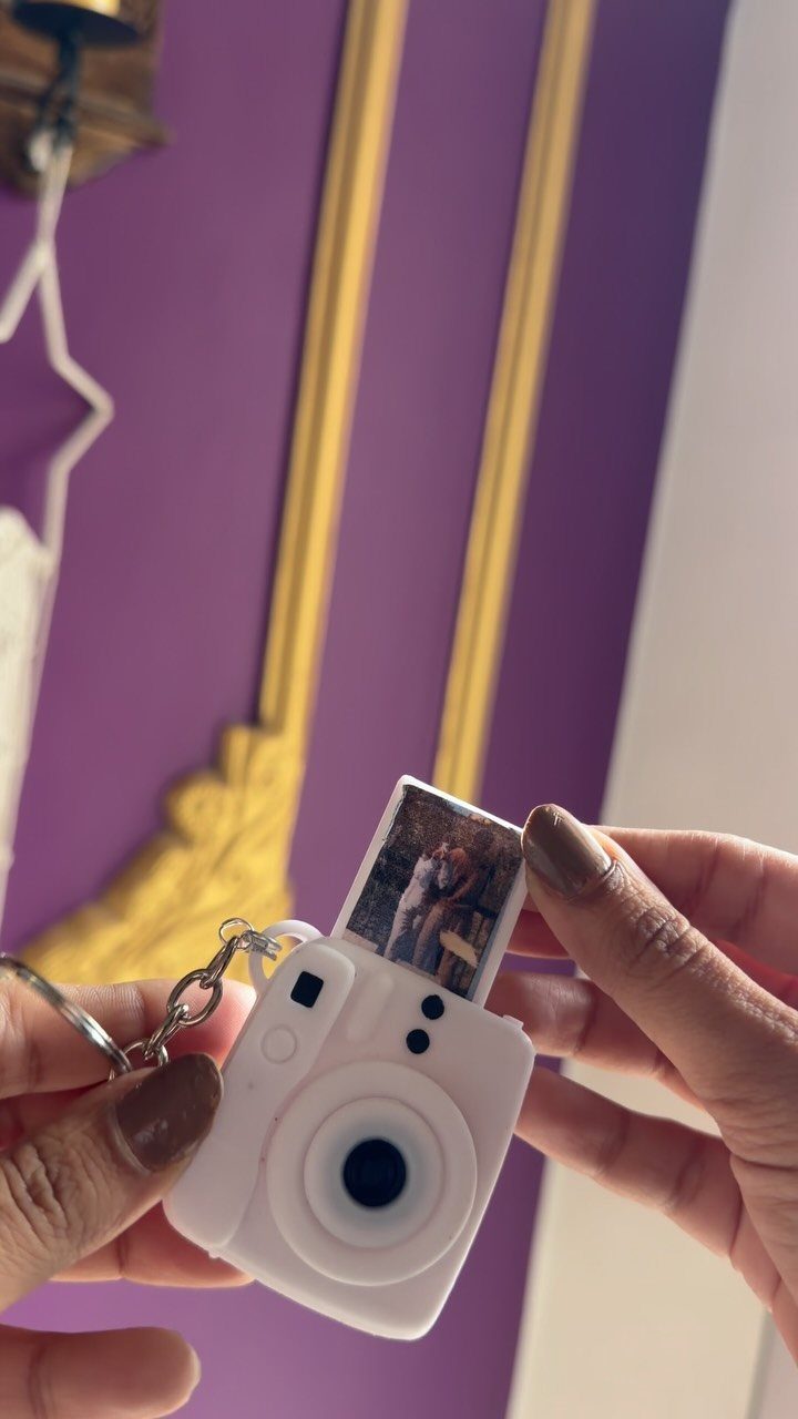 White camera-shaped keyring with a small photo of a couple being pulled out.