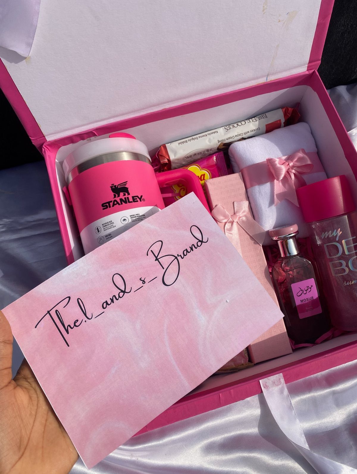 Pink gift box containing a Stanley tumbler, perfume, body mist, and a handwritten envelope.