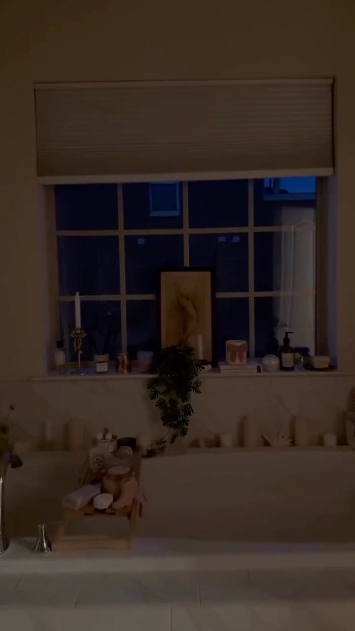 Bathtub with a wooden caddy holding spa products in a dimly lit bathroom.