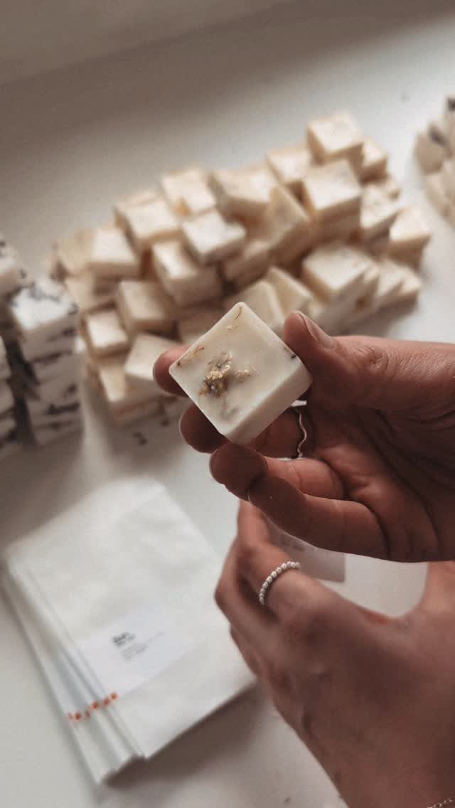 Hands holding a white botanical wax melt cube with more cubes in background