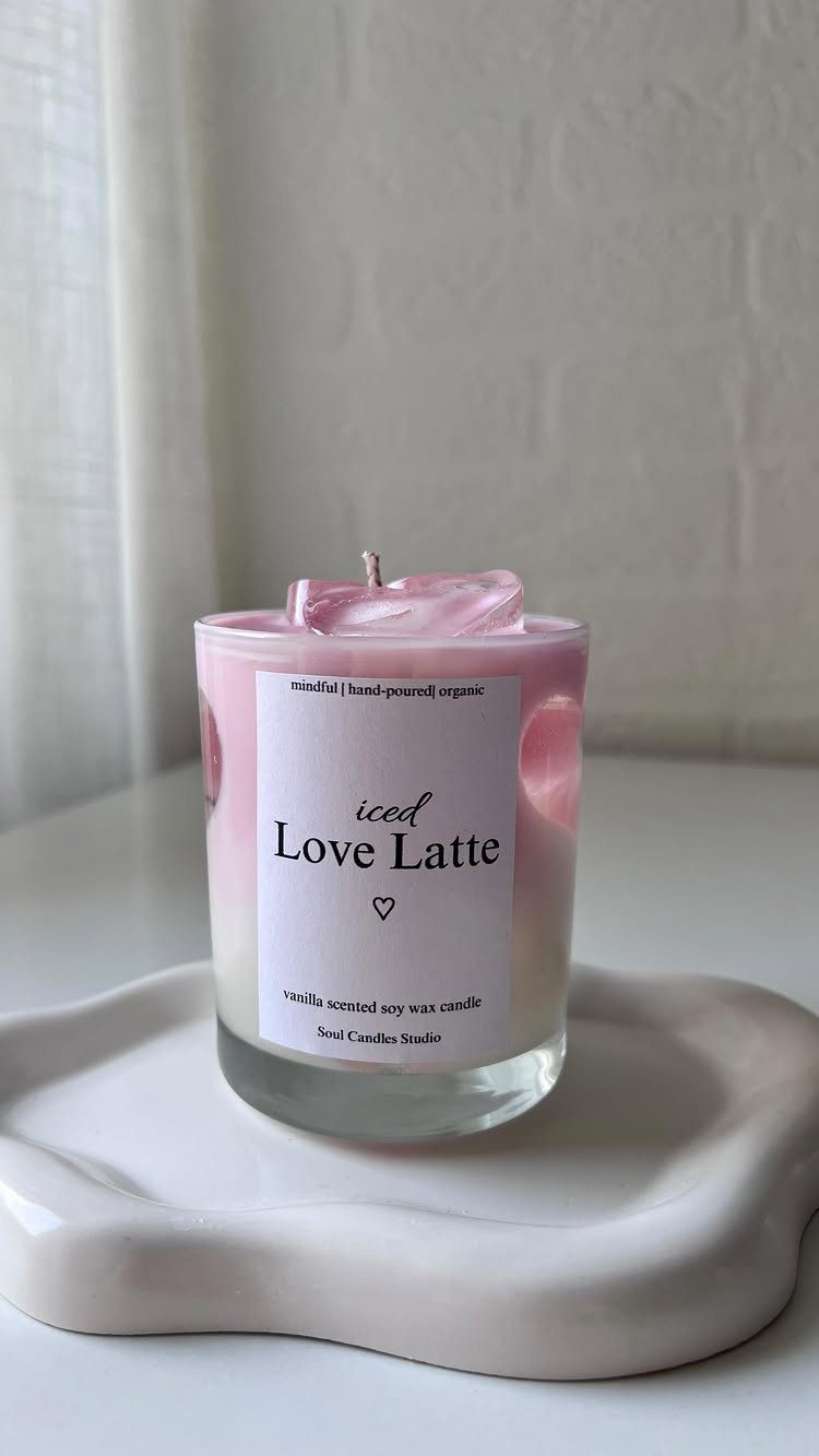 Pink and white layered candle in a glass jar on a white tray