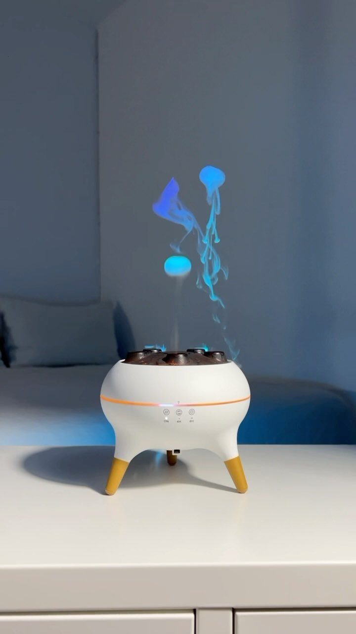 White essential oil diffuser emitting blue illuminated mist on a white table