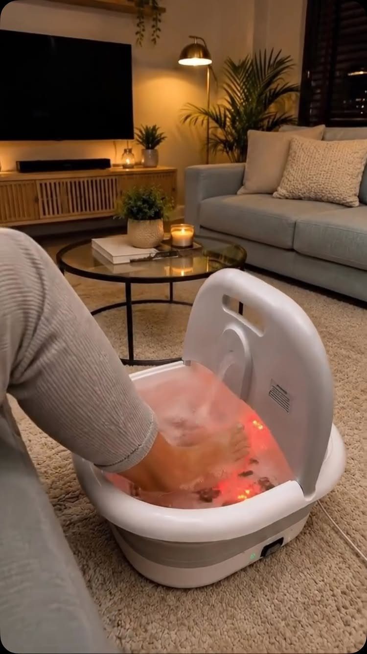 Feet soaking in a white electric foot spa basin in a cozy living room